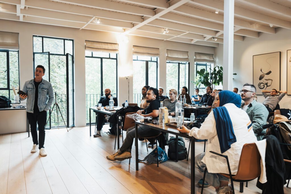 Diverse group attending workshop, focused on speaker presenting in modern indoor setting.